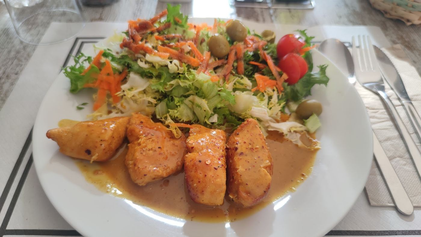 Trozos de pollo jugoso con ensalada fresca de tomate y aceitunas.